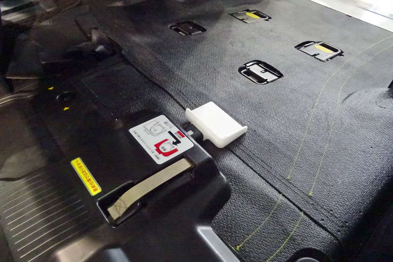 中央に見える白いフックで電動車いすをガッチリとロックする。後方側の白いペダルを踏むと電動車いすがリリースされる