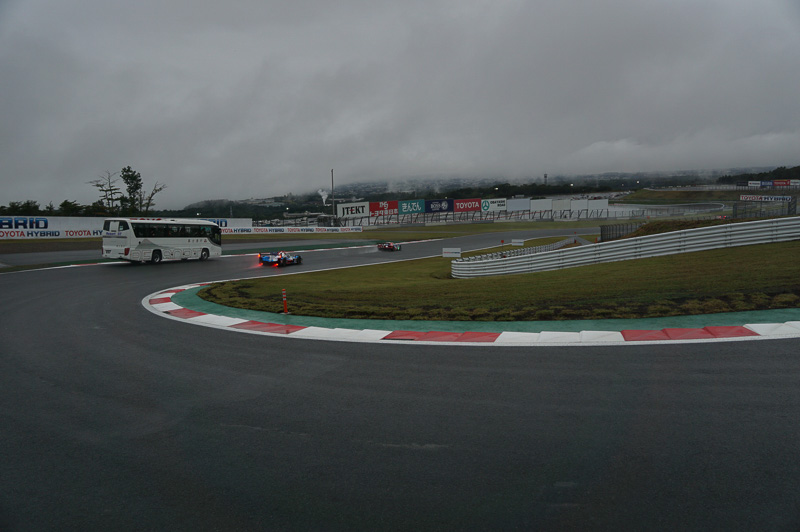 1コーナーから2コーナーへ抜けていくところ、バスの横をレーシングカーがすり抜けていく