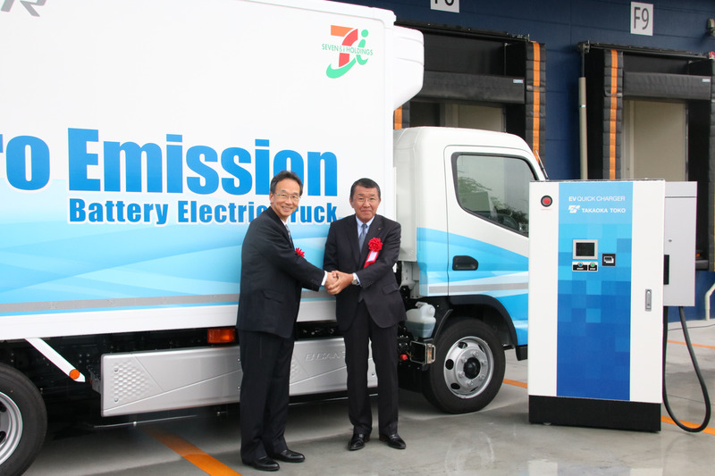 三菱ふそうトラック・バスの松永氏とセブン-イレブン・ジャパンの古谷氏がeCANTERの前で握手