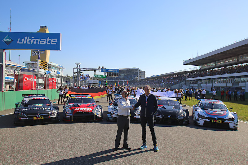 15日のレース前のセレモニーで、並んだGT500とDTMのマシンの前で握手する坂東正明代表とゲルハルト・ベルガー代表