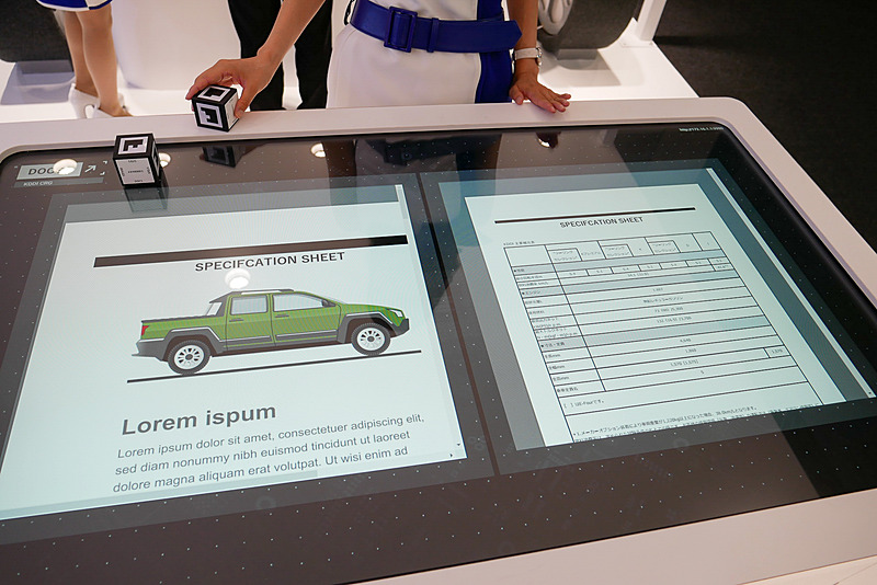 KDDIの「ガラスディスプレイ」を利用し、カーディーラーなどで顧客にクルマの仕様などを説明する用途に活用することを想定したデモ展示