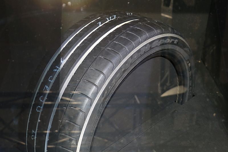 暗いケースの内部に置かれたタイヤをフラッシュ撮影したシーン。側面やグルーブの内側などが白く光っている