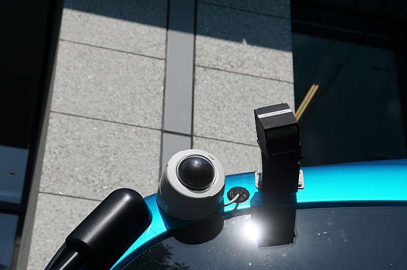 車両の左右にもLiDAR（黒）が取り付けられている。白い台座の黒いものはカメラで、これはSBドライブの運行用