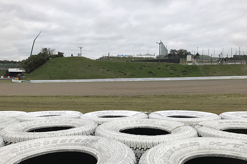 右側がデグナー1つ目、左側がデグナー2つ目。立体交差のトンネルも見える。正面の白、青のテントは130Rのオアシス。前日最後の撮影はやや左の土手の上からデグナー2つ目と撮った