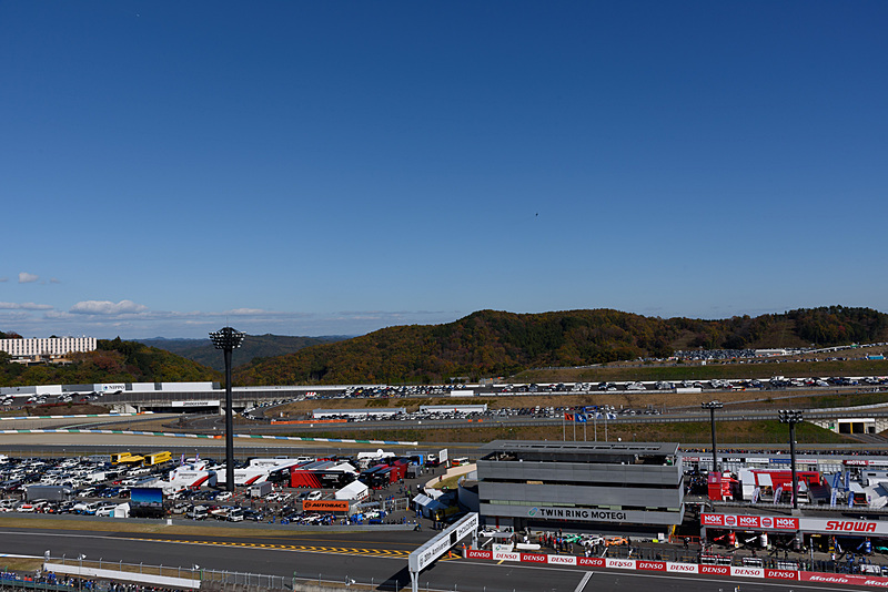 メインストレート奥からF-2B戦闘機が飛来。ツインリンクもてぎのメインの建物の上にある黒い点がF-2B戦闘機