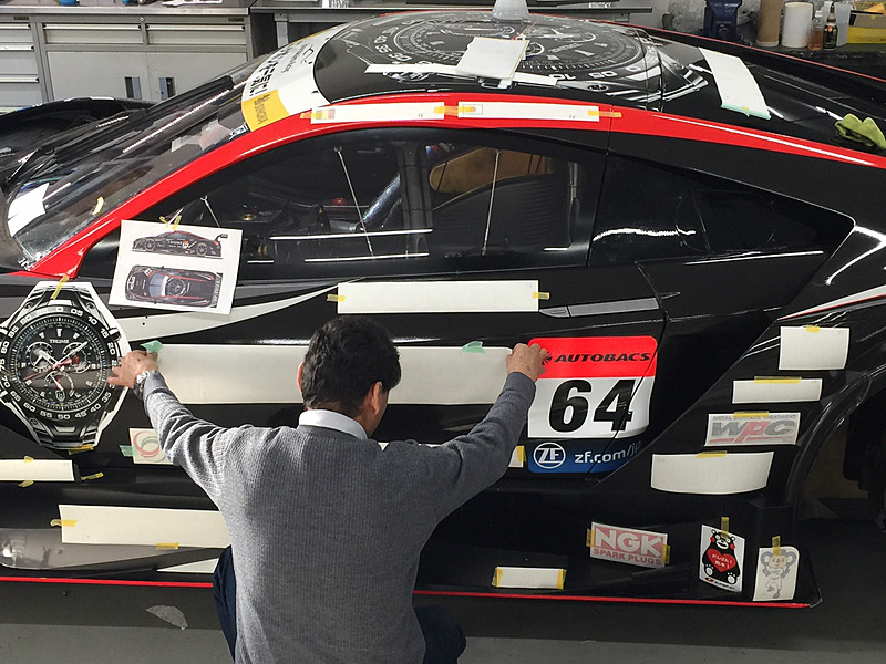 シートの貼り付けが完了したあとに、スポンサーのロゴの位置を決める中嶋総監督