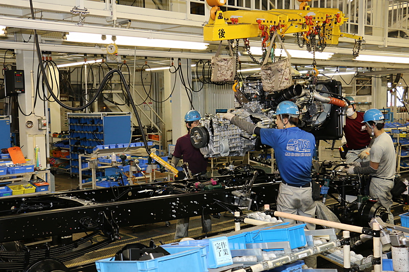 屋内の上層で運ばれるエンジンとトランスミッションを一体化させた「パワーパック」をシャシーフレームに組み付ける