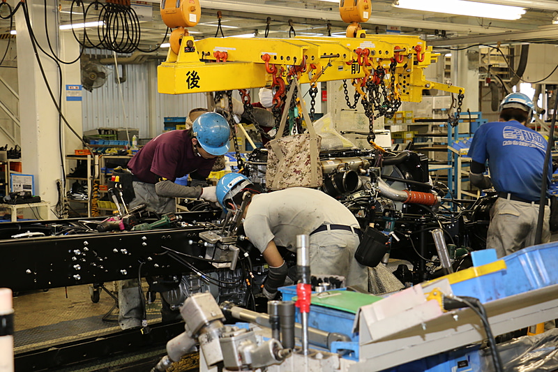 屋内の上層で運ばれるエンジンとトランスミッションを一体化させた「パワーパック」をシャシーフレームに組み付ける