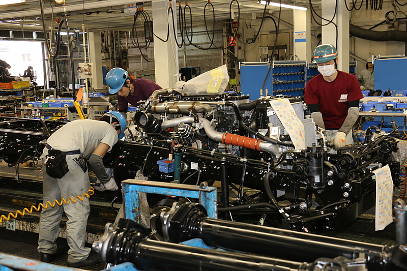 屋内の上層で運ばれるエンジンとトランスミッションを一体化させた「パワーパック」をシャシーフレームに組み付ける