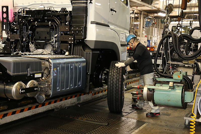 前輪の取り付けシーン。転がしていったタイヤを、フロアごと持ち上げてハブボルトに差し込む