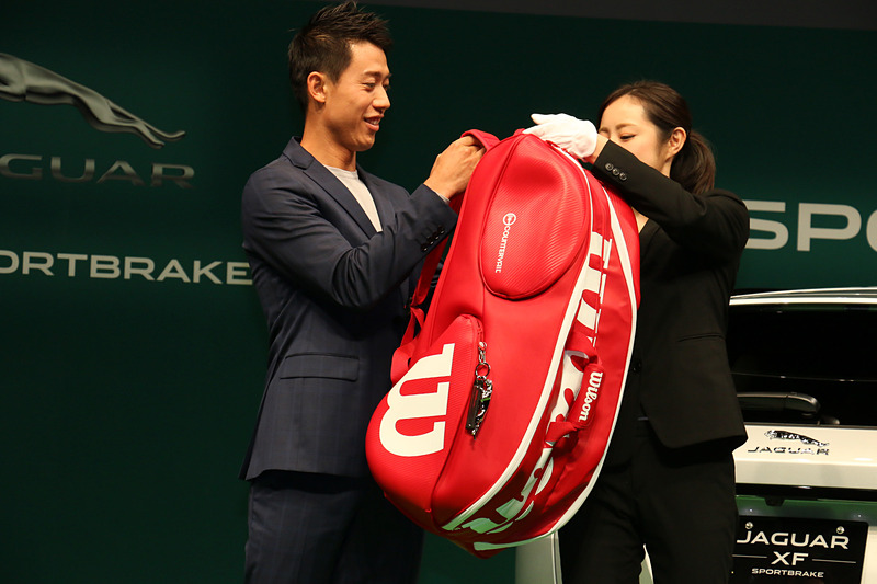 ラケットバッグを背負ってジャガーブランドチャームを紹介。ジャガーのブランドロゴが滑らかな金属で立体化されている