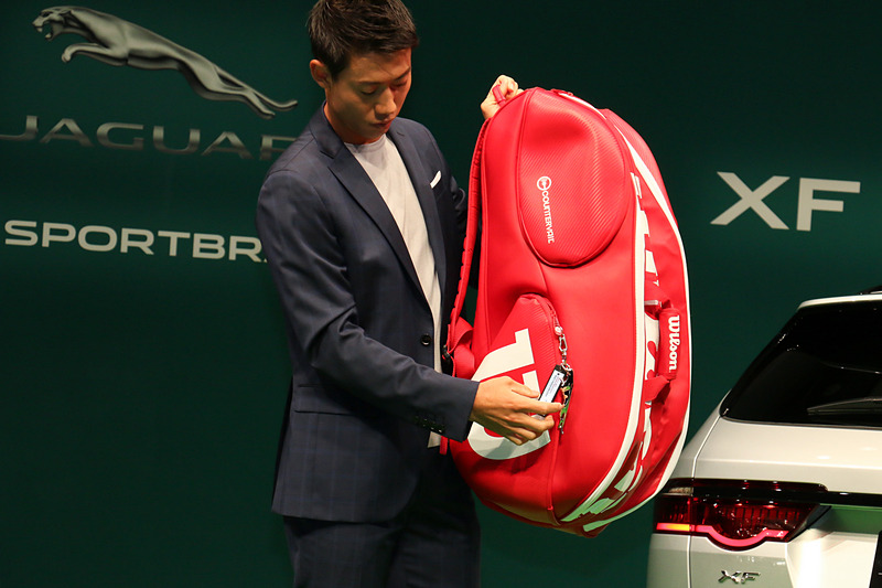 ラケットバッグを背負ってジャガーブランドチャームを紹介。ジャガーのブランドロゴが滑らかな金属で立体化されている