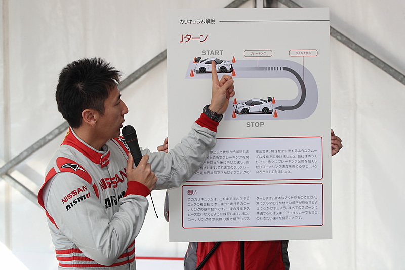 ステアリングの操作とドライビングポジション、ステージ1のプログラムについて説明する松田選手。サーキットを走る場合のドライビングポジションは、ステアリングの頂点を掴んだときに腕が伸びきらない状態でブレーキがしっかり踏める距離がベストな位置とのこと