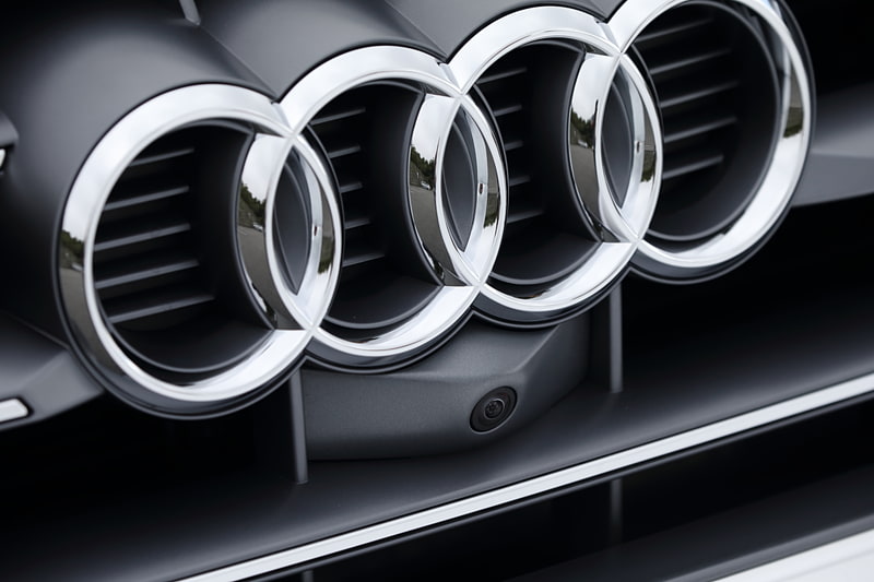 新しいQ5シリーズではフロントグリル（写真中央）やドアミラー、リアハッチなどのカメラ、フロントバンパー両サイドのレーダーセンサー（写真右）などに加え、フロントウィンドウのカメラ、前後の超音波センサーなどを標準装備。アダプティブクルーズコントロール、アウディ プレゼンス シティ、アウディ プレゼンス リア、サラウンドビューカメラなどの先進装備を機能させる