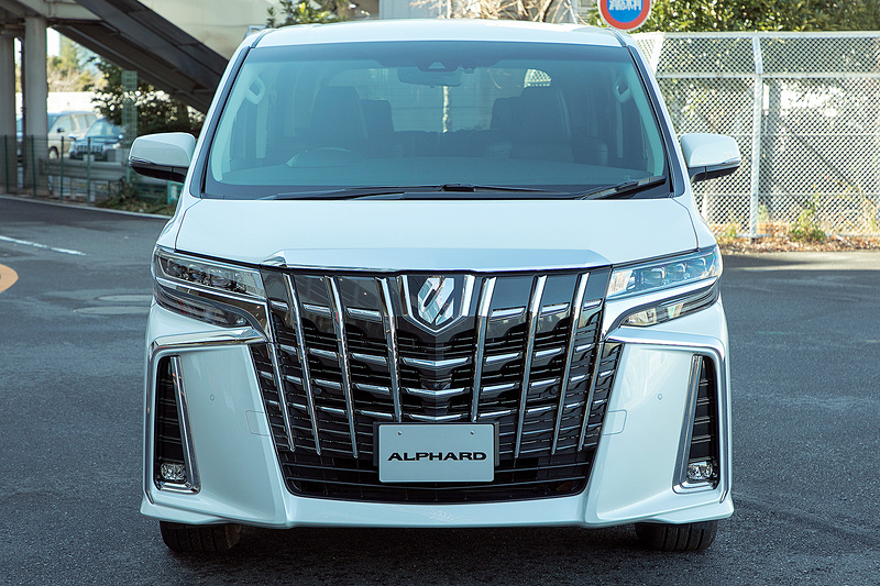 アルファード SC。7人乗りでエンジンはV型6気筒DOHC 3.5リッター。駆動方式は2WD（FF）でミッションはDirect Shift-8AT。撮影車のボディカラーはホワイトパールクリスタルシャイン（有料色）となっている。エアロタイプとなり、バンパーはエアロ専用。このタイプはフロント、リアともにメッキ加飾の部分を横へ伸ばすことでワイド感を出すデザイン。もともと大柄な車種だがより迫力が増している
