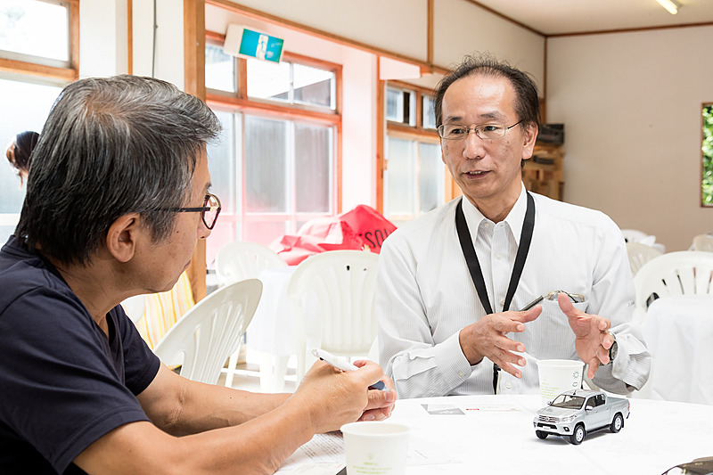 試乗の合間に開発担当者にインタビュー。8代目となるハイラックスは、当初は日本導入の予定がなく、日本で販売するために必要な装備の追加に苦労したとのこと。左フロントのサイドアンダーミラーは大型ヘッドライトの影響からアームが長くなり、リアのナンバープレートは上側からベースを伸ばして固定しているという