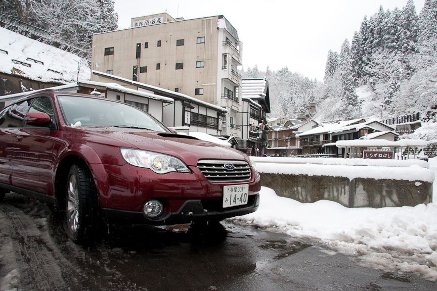 一夜明けた銀山温泉とレガシィ アウトバック 2.5XT EyeSight。路面には雪が残るが、天気は快方へと向かう