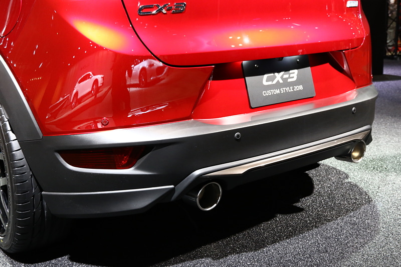 ディーラーオプションとなるMAZDASPEEDのエクステリアパーツを装備したCX-3。マフラーはMAZDASPEEDの特別仕様で、参考出品となる。足まわりやブレーキもカスタマイズパーツを装着していて、ブレーキは赤の塗装を施したペイントキャリパー、ホイールはRAYS製の「WALTZ S7」、タイヤはブリヂストン「POTENZA S001」。サスペンションは、MAZDASPEEDの車高調整式で、フロント30mm、リア25mmを下げている。ブレーキとタイヤ・ホイール、サスペンションともに参考出品となる