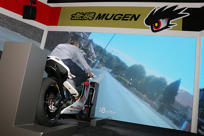 「マン島TTレース」参戦の電動バイク「神電 四」は、実際に車両にまたがって、マン島を走行する映像に合わせて右左にハングオンする体験コーナーに利用されていた