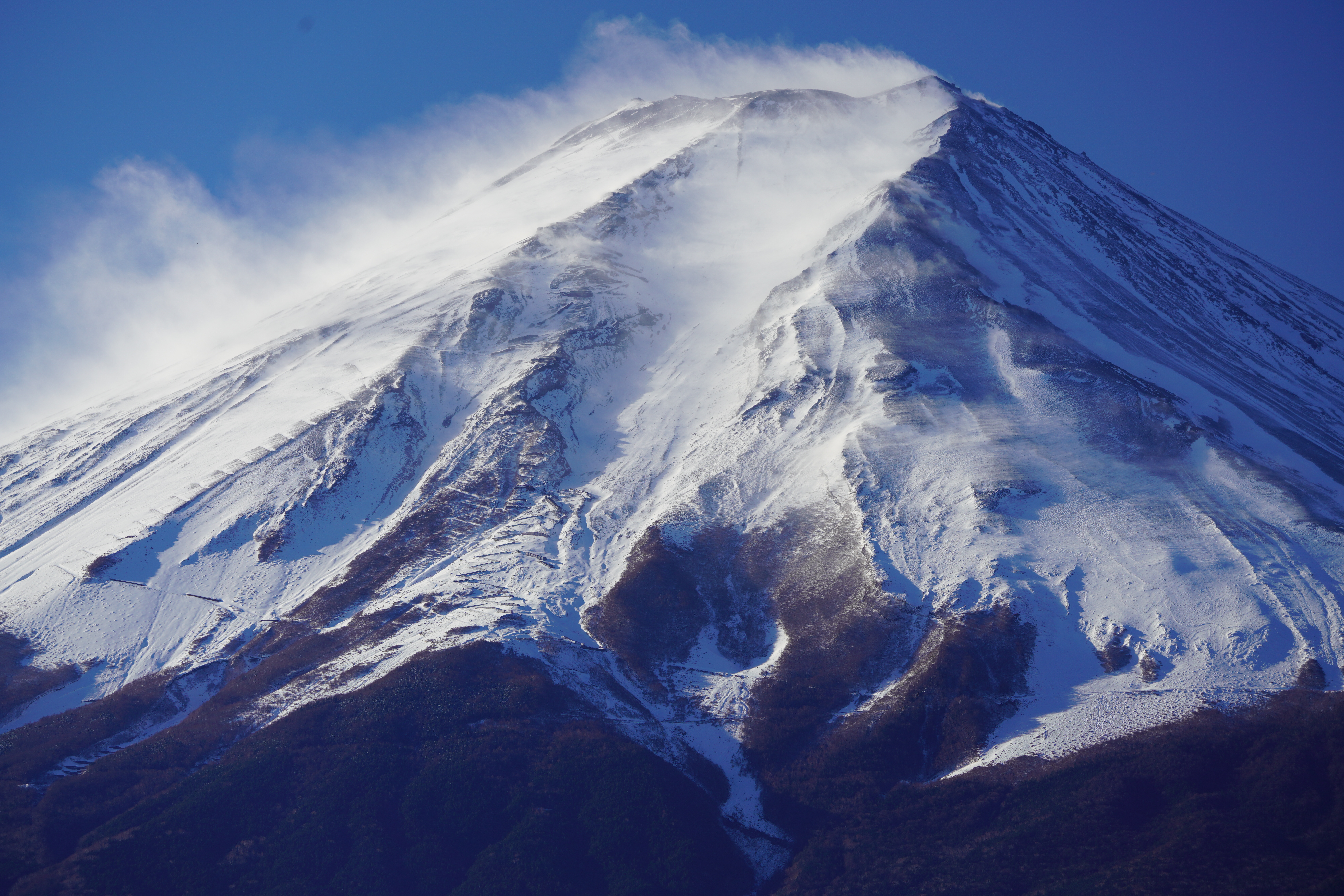 【作例】さらに望遠で強風に舞う山頂付近の雪煙をアップで狙う。積雪が薄くなり、斜光線で照らされたことで、山肌の質感が驚くほど高精細に再現されている。撮影データ/ソニーα7R III FE100-400mm F4.5-5.6 GM OSS（238mm域） 絞り優先オート F8 1/250秒 ISO160 WB：AUTO（ホワイト優先） クリエイティブスタイル:風景