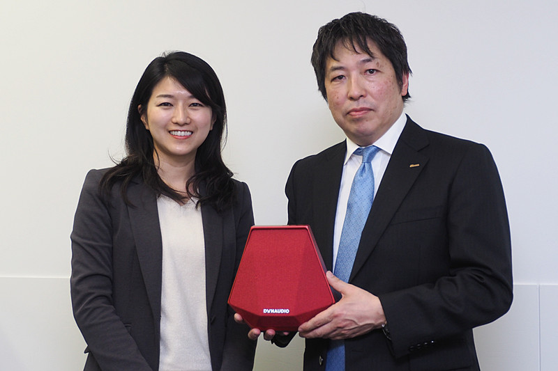 DYNAUDIO JAPAN株式会社 代表取締役の前田正人氏（右）とフォルクスワーゲン グループ ジャパン株式会社 営業本部 商品企画課 プロダクトプランナーの水野真菜美氏（左）。前田氏が手にしているのは発売予定のワイヤレススピーカー「DYNAUDIO Music 1」