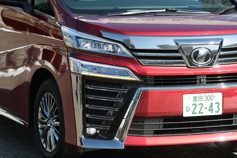 ヴェルファイアではフロントグリルをボディ同色部分で上下に分割し、2段式のヘッドライトデザインを強調。ヘッドライトはアルファードと同じく3眼LEDヘッドライト＋LEDクリアランスランプを標準装備