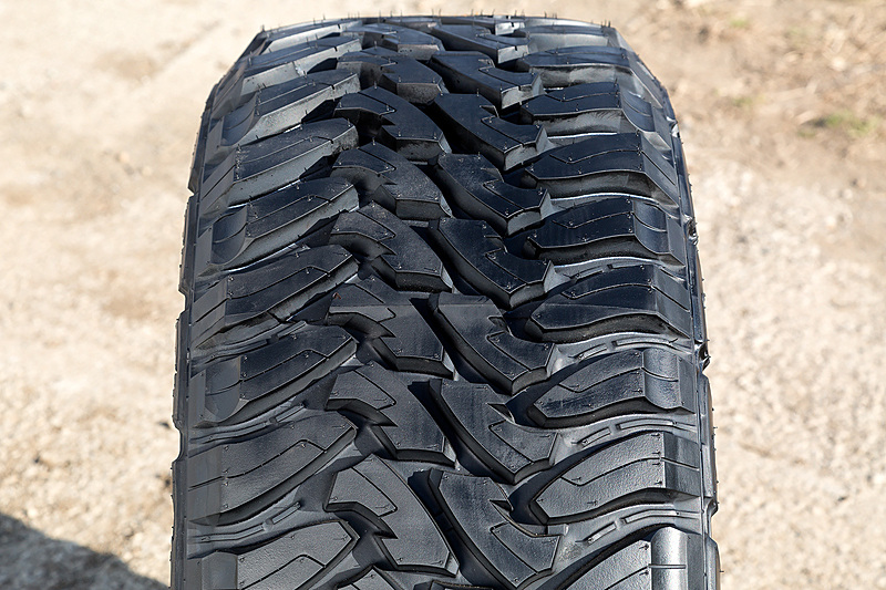 2003年に米国などで出荷が始まった本格的なオフロードタイヤ「OPEN COUNTRY M/T」。アグレッシブな外観、あらゆる路面を走破できるパフォーマンス性能と耐久性、優れたユニフォミティといった性能を引っさげて2018年に日本市場に導入することが決定。耐外傷性の向上を目的にサイドウォールにバットレスデザインを採用するとともに、トラクションやハンドリング性能の向上を図るべく周方向に段差を設けたブロック形状を採用。また、カーカスプライを3枚並べる「3プライハイターンアップ構造」の採用とともに、高硬度ビードフィラーや高強力スチールベルトなどによって耐久性を高めた。なお、発売されて以降、マイナーチェンジなしで販売される珍しいタイヤとなっている