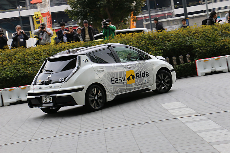 多数の報道陣が見守る中、実証実験用車両はEV（電気自動車）のリーフらしく静かにスタート。公道に出てすぐの交差点で赤信号を待ち、青信号を認識して横浜ワールドポーターズに向けて再スタートしていった