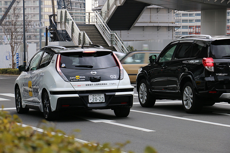 多数の報道陣が見守る中、実証実験用車両はEV（電気自動車）のリーフらしく静かにスタート。公道に出てすぐの交差点で赤信号を待ち、青信号を認識して横浜ワールドポーターズに向けて再スタートしていった