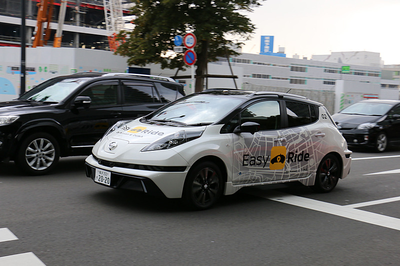 多数の報道陣が見守る中、実証実験用車両はEV（電気自動車）のリーフらしく静かにスタート。公道に出てすぐの交差点で赤信号を待ち、青信号を認識して横浜ワールドポーターズに向けて再スタートしていった