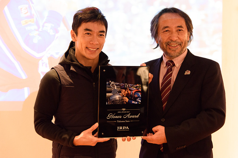 トークショーに登場した佐藤琢磨選手（左）と主催となる日本レース写真家協会の会長 小林稔氏（右）