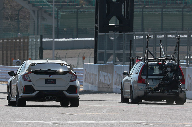 撮影用車両の背後に乗ったカメラマンがバトン選手を撮影した