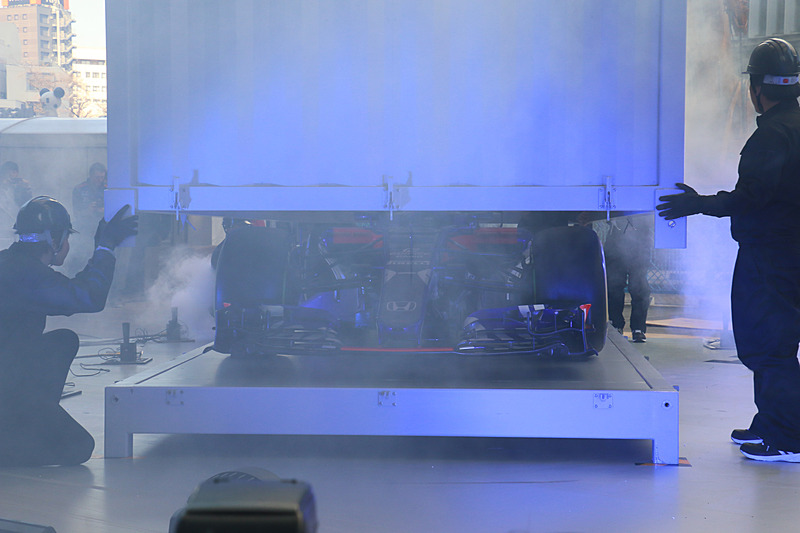 クレーンを使ってステージ上に移動されたコンテナ内からニューマシンが登場