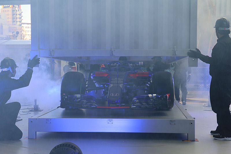 クレーンを使ってステージ上に移動されたコンテナ内からニューマシンが登場