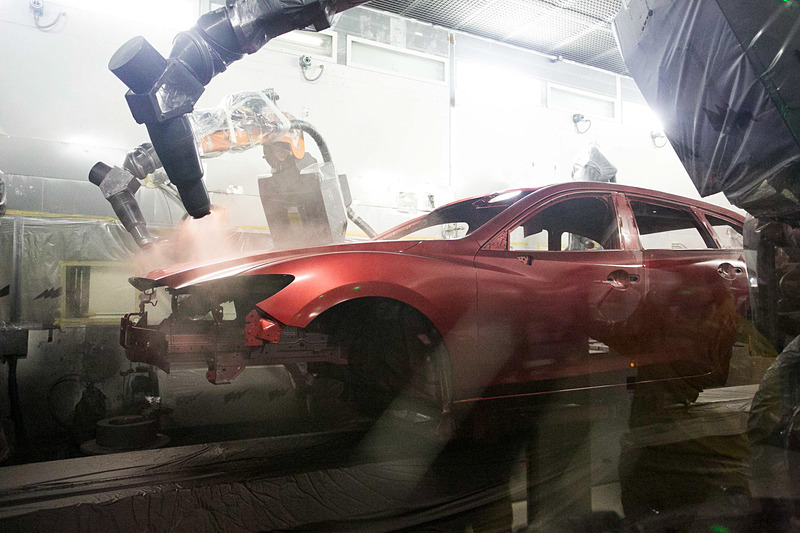 異なる色でも塗料が混ざることなく塗布できる塗装ライン。ホコリなどのゴミが塗装に入り込んでしまわないように機械は全てビニールで覆われていて、塗料が舞ってしまわないように風の流れも考えられている