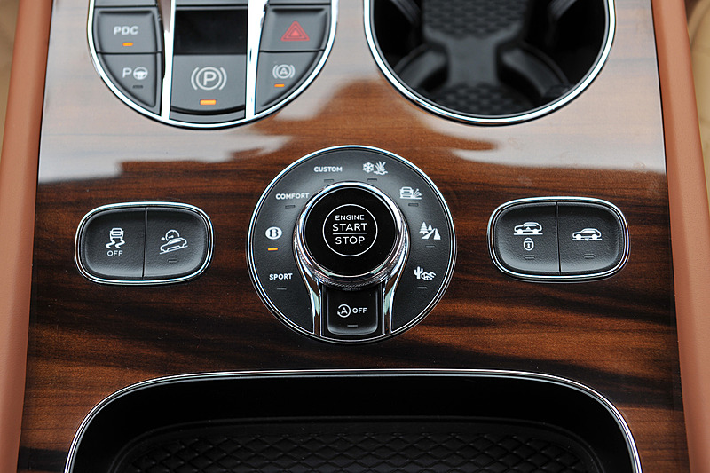 ベージュを基調とし、レザーやウッドパネルを贅沢に使用したインテリア。センターコンソールに8インチのタッチスクリーン式インフォテイメントシステムを標準装備するほか、ダッシュボード中央のアナログ時計が目を引く。センターコンソールには8種類のドライブモード（スポーツモード、ベントレーモード、コンフォートモード、カスタムモード、雪道/草地モード、泥道モード、砂利道モード、砂地モード）を統合制御する「ドライブダイナミクスコントロール」のコントロールダイヤルが備わる