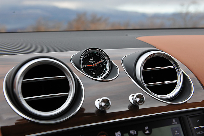 ベージュを基調とし、レザーやウッドパネルを贅沢に使用したインテリア。センターコンソールに8インチのタッチスクリーン式インフォテイメントシステムを標準装備するほか、ダッシュボード中央のアナログ時計が目を引く。センターコンソールには8種類のドライブモード（スポーツモード、ベントレーモード、コンフォートモード、カスタムモード、雪道/草地モード、泥道モード、砂利道モード、砂地モード）を統合制御する「ドライブダイナミクスコントロール」のコントロールダイヤルが備わる