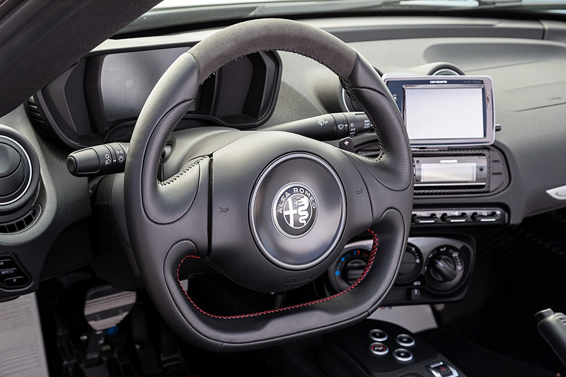 ブラックを基調にした4C スパイダーのインテリア。カーボンファイバー製のボディセルが目を引くとともに、フラットボトムのステアリングホイールやアルミニウム軽合金製のフットレスト＆ペダル、スポーツシートなどでレーシーな雰囲気を演出
