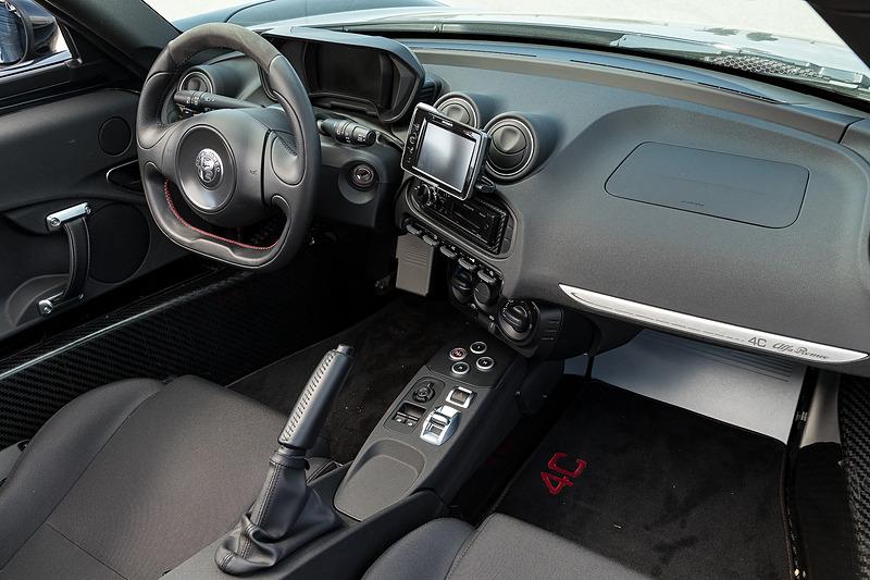 ブラックを基調にした4C スパイダーのインテリア。カーボンファイバー製のボディセルが目を引くとともに、フラットボトムのステアリングホイールやアルミニウム軽合金製のフットレスト＆ペダル、スポーツシートなどでレーシーな雰囲気を演出