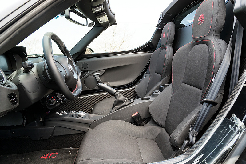 ブラックを基調にした4C スパイダーのインテリア。カーボンファイバー製のボディセルが目を引くとともに、フラットボトムのステアリングホイールやアルミニウム軽合金製のフットレスト＆ペダル、スポーツシートなどでレーシーな雰囲気を演出