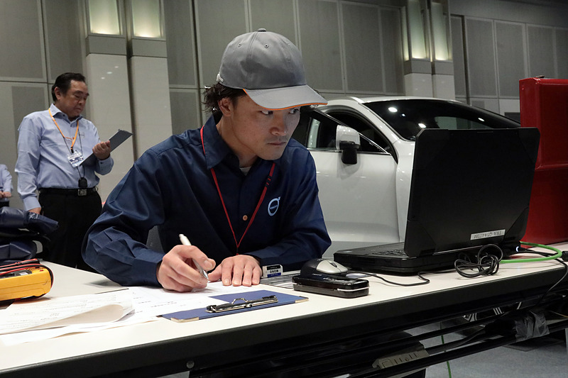 技能試験中の光景。かなり難しい問題設定だったようで、テクニシャンといえども苦戦している方が多かった。なお、いまどきはアレコレ外してチェックするのではなく、診断機をフル活用するので修理といっても診断中はPCを見る時間のほうが長い