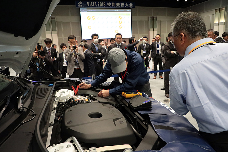 技能試験中の光景。かなり難しい問題設定だったようで、テクニシャンといえども苦戦している方が多かった。なお、いまどきはアレコレ外してチェックするのではなく、診断機をフル活用するので修理といっても診断中はPCを見る時間のほうが長い