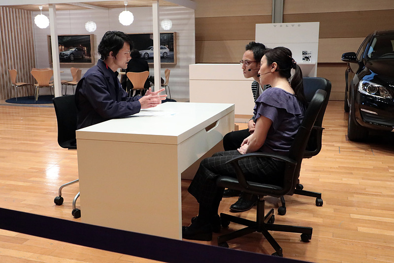 こちらはショールームへユーザーが来店した時の対応を見る試験。ショールームのセットが組まれていて、サービスアドバイザー、サービスマネージャー、そしてテクニシャンとチーム（2名のケースもある）で対応する。技能試験で直したクルマを引き取りに来たオーナーという設定の客役への対応や、12ヶ月点検、用品の購入相談の対応なども審査された