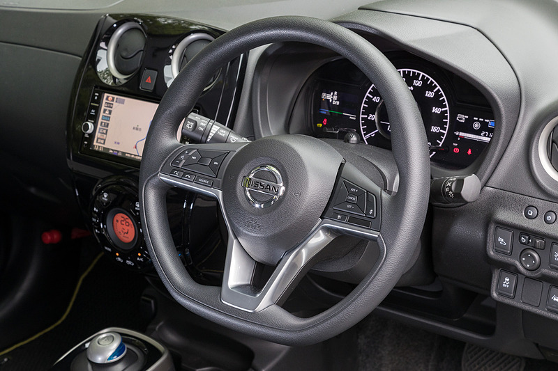 ブラックを基調にしたノート C-Gearのインテリア。なお、ベース車のノートは2017年9月に仕様向上が図られており、高速道路などを使った長距離ドライブ時にドライバーの運転負荷を低減する「インテリジェントクルーズコントロール」、意図せずに走行車線から逸脱しそうなときに車線内に戻るステアリング操作を支援する「インテリジェントLI（車線逸脱防止支援システム）」を新たに採用して利便性や安全性を向上。撮影車のステアリングにはインテリジェントクルーズコントロールの設定ボタンが備わっている
