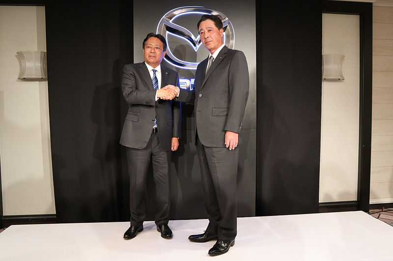 記者会見最後のフォトセッションで握手する丸本明氏（左）と小飼雅道氏（右）