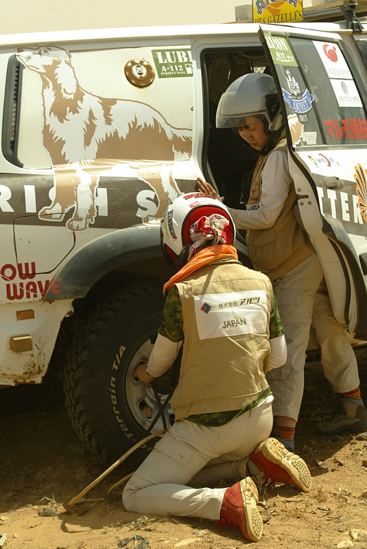 後席を取り外した車内にエアタンクを積み、路面の変化に合わせて細かくタイヤ空気圧を変えて走っていました。砂地にひざまずいて作業しているのは私……。首にぐるぐる巻きにしているストールは、砂よけと強い陽射し対策です