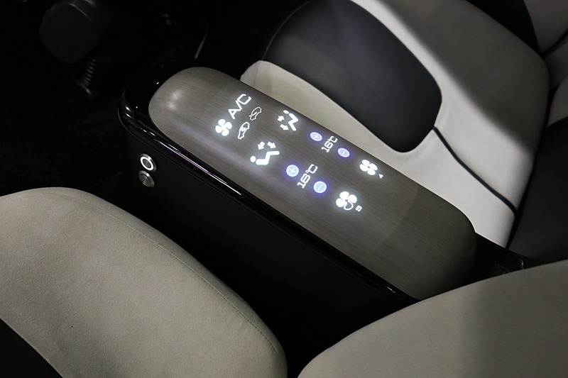 デラグラスでは樹脂表面に焦点を結ばせることが可能になり、内側から投射した映像をディスプレイのように表示できる。展示では木目調パネルのアームレストにエアコンやオーディオの情報が次々に表示されていた