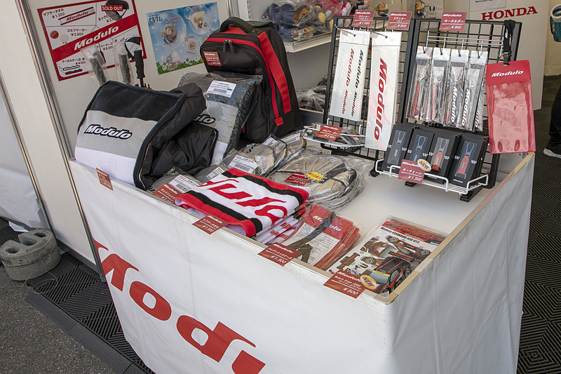物販コーナー。ホンダアクセスのマスコットキャラ「くるタム」のぬいぐるみを購入した人には、サーキットごとの「ご当地くるタム」が描かれた特製トートバッグを数量限定でプレゼント。Moduloスマイルの水村リアさんが持つ鈴鹿仕様のトートバッグには、鹿の角を付けた「すずタム」が描かれている