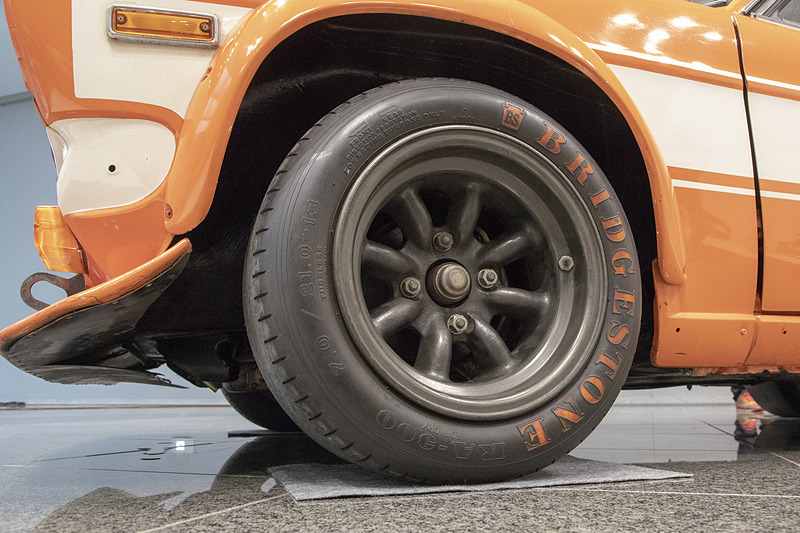 バンパーとグリルまわりの加飾パーツが取り去られている。ライトも外されていてカバーが付く。大型のスポイラーも装着。下を覗くと裏面に飛び石などから防御するためのゴムが貼ってあった