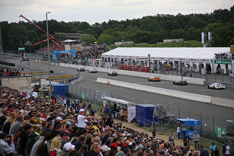 順位争いで連なるマシンを観戦する観客